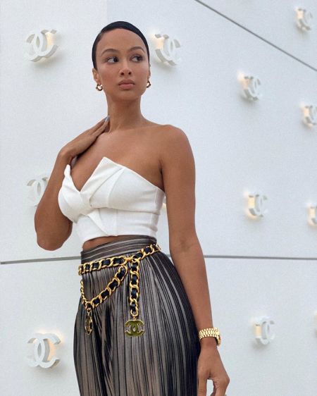 Draya Michele in a white top and black pants poses for a picture.